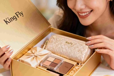 A woman smiling as she unboxes a luxury GWP gift set containing a gold cosmetic pouch.