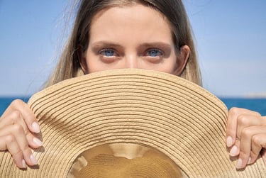 Close-up of blue eyes of a young girl partially hidden behind a hat