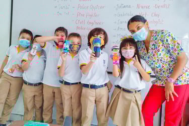 a group of children and the teacher posing for a picture, after finishing a creative task