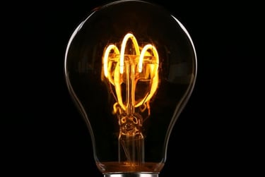 A glowing light bulb with visible filament against a black background.