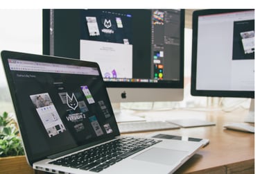 A pic of a laptop with two external monitors behind it
