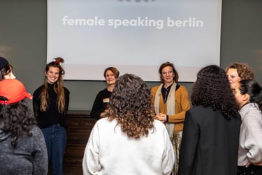 Women in circle, smiling and listening to each other, in workshop room, beamer logo female speaking