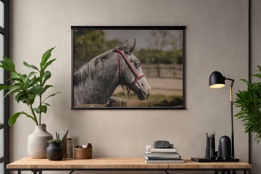 A framed dapple grey horse print hanging above a wooden desk with a lamp and green plants.