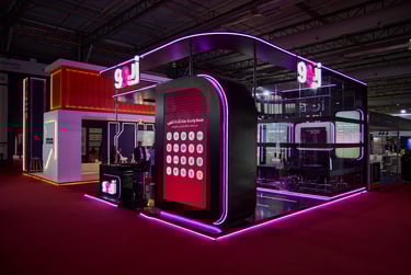 Modern neon-lit exhibition stand with purple LED accents and digital display at a trade show.