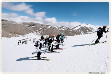 Line of backcountry skiers climbing a snowy Crete mountain slope under a bright blue sky