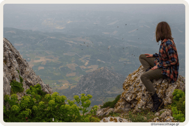 Woman sitting with a view of the valley in the mountains of Crete, surrounded by nature