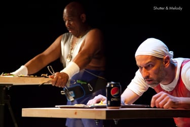 Die Schauspieler auf der Bühne bereiten sich auf das Essen an ihren Tischen vor.