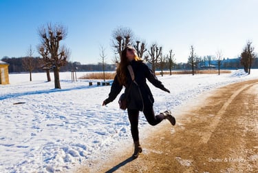 Eine Besucherin tanzt auf dem Gelände von Schloss Moritzburg im Winter.