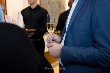 Mann in blauer Jacke mit einem Glas Sekt in der Hand.