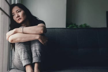 a sad woman sitting on a couch in a living room