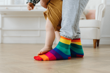 Adult feet with baby feet standing on top of them