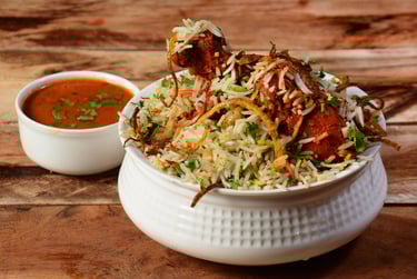 Hyderabadi chicken biryani served with raita, garnished with fried onions and fresh herbs
