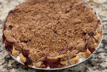 Freshly baked peach crumble pie with a golden brown streusel topping on a granite countertop.