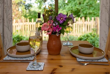 a table with a vase of flowers and a glass of wine