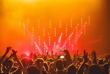 a crowd of people standing in front of a stage with bright lights