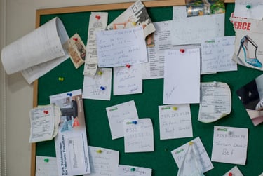a bulletin board with a green board with notes and a mask mask