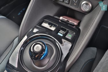 Close-up of a Nissan Leaf electric car gear selector and eco mode button on the center console.