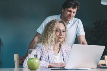 a man and woman sitting at a table with a laptop