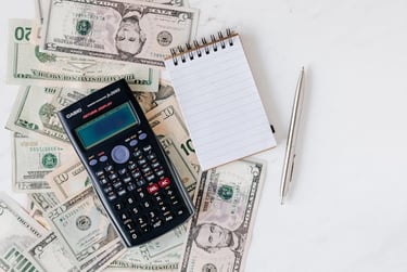 calculator, money, pen, and paper representing making a budget and overall planning finances
