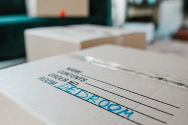 Cardboard moving box labeled bedroom in blue ink, ready for home relocation and packing.