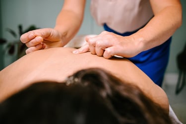 Professional acupuncturist inserting a sterile needle into a patient's back for dry needling therapy.