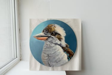 painting of an Australian kookaburra bird on a circular canvas displayed against a white wall.