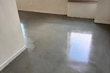 Polished grey microcement flooring in a modern room with white walls.