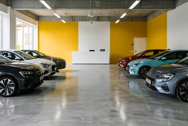 Modern car showroom with rows of vehicles parked on a polished concrete floor against a wall with ye