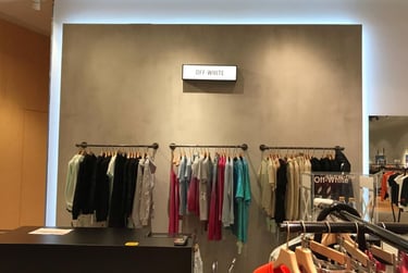 Off-White luxury streetwear clothing on hanging display racks in a modern boutique retail store.