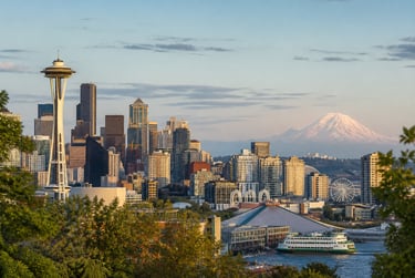 Seattle skyline featuring the Space Needle and Mount Rainier under a sunset sky.