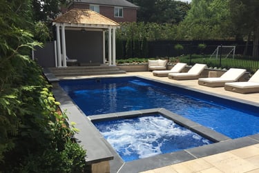 Luxury backyard swimming pool with built-in hot tub, poolside lounge chairs, and a white pillared gazebo.