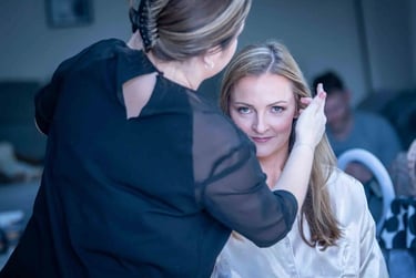 Professional bridal makeup artist applying finishing touches to a blonde bride on her wedding day.