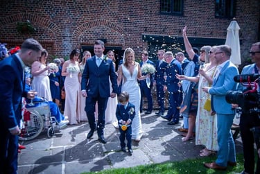 A happy bride and groom walking through a confetti toss at their outdoor wedding ceremony.