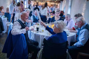 Elderly guests talking and laughing at a wedding reception seated at a round banquet table.