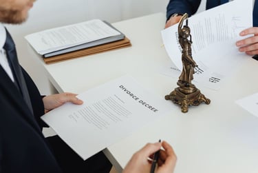 Revisión de documentos legales en una oficina, con estatua de la justicia sobre el escritorio.