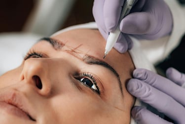 Técnica profesional realizando el mapeo de cejas para microblading en una mujer para maquillaje perm