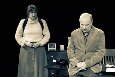 Man leaning on desk with woman standing behind.