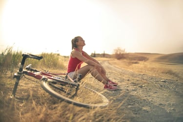 Biker sitting on side of the dirt path with eyes closed, relaxed, regulating breathing.