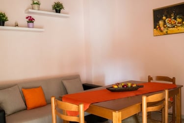 Cozy dining area featuring a wooden table with an orange runner and a grey sofa.