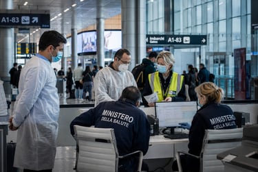 Italian health ministry staff in masks conduct passenger screenings at a busy airport terminal.