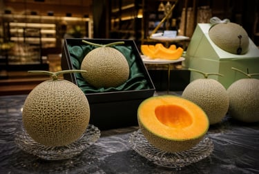 Premium Japanese Crown melons displayed in luxury gift boxes and sliced on a marble counter.