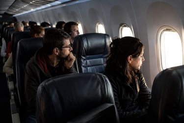 Passengers looking out window during a commercial flight inside an airplane cabin.