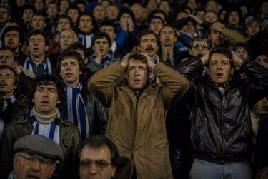 Devastated football fans with hands on heads reacting to a loss in a crowded stadium crowd.
