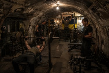 Men training in an underground bunker gym with weights and a Ukrainian flag.