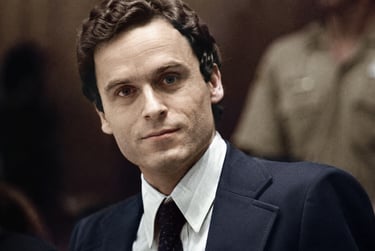 A colorized close-up portrait of Ted Bundy in a courtroom wearing a navy suit and tie.