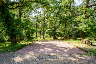 Terrain de pétanque privé en gravier, entouré de verdure et d’arbres, idéal pour les convives.