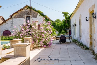 Terrasse en pierre pleine de charme avec vue sur les bâtisses du domaine, un cadre idéal.