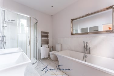 Salle de bains moderne avec douche d’angle à l’italienne, baignoire blanche et miroir.