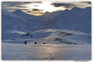 People hiking across a vast snowy mountain landscape at sunset in Crete