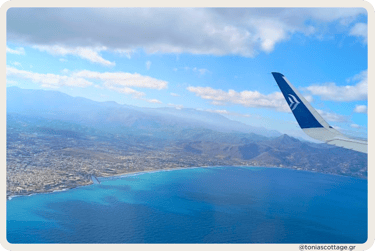 View of Crete from an airplane window, showcasing the deep blue sea and rugged mountains
